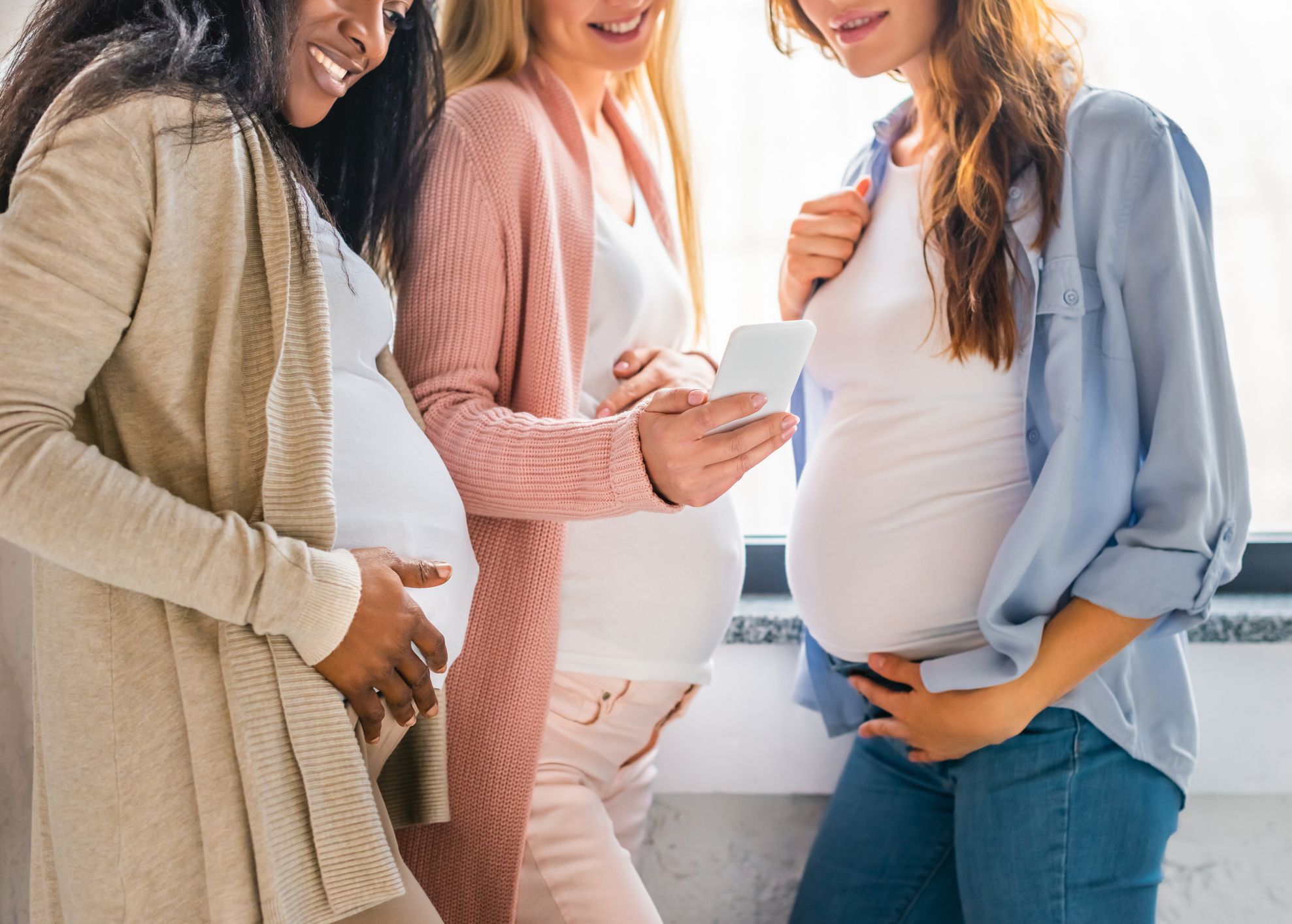 Three pregnant women smiling